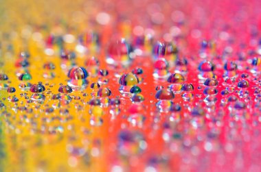 Su damlacıklarının sanatsal bir görüntüsü çok renkli arkaplandan güzel renk dizilerini yansıtıyor.