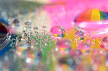 Su damlacıklarının sanatsal bir görüntüsü çok renkli arkaplandan güzel renk dizilerini yansıtıyor.