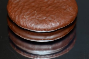 Yansıtıcı bir arka planda izole edilmiş Twinkie 'lere benzeyen beyaz kremayla doldurulmuş bir çikolatalı pasta..