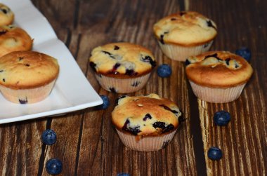 Yeni pişmiş yaban mersinli keklerin bir çeşidi, izole edilmiş ahşap bir yiyecek damlasının üzerine serilmişti..