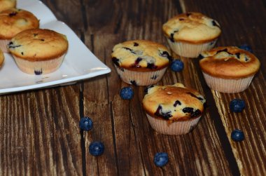Yeni pişmiş yaban mersinli keklerin bir çeşidi, izole edilmiş ahşap bir yiyecek damlasının üzerine serilmişti..