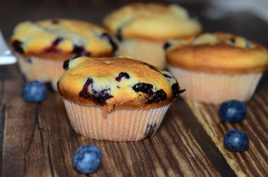 Yeni pişmiş yaban mersinli keklerin bir çeşidi, izole edilmiş ahşap bir yiyecek damlasının üzerine serilmişti..