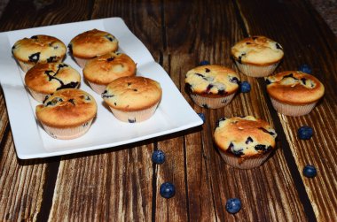 Yeni pişmiş yaban mersinli keklerin bir çeşidi, izole edilmiş ahşap bir yiyecek damlasının üzerine serilmişti..