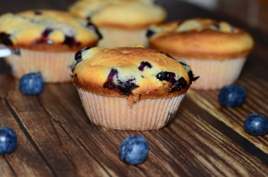 Yeni pişmiş yaban mersinli keklerin bir çeşidi, izole edilmiş ahşap bir yiyecek damlasının üzerine serilmişti..