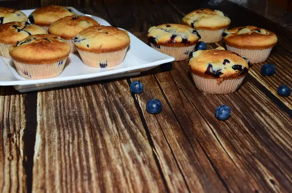 Yeni pişmiş yaban mersinli keklerin bir çeşidi, izole edilmiş ahşap bir yiyecek damlasının üzerine serilmişti..