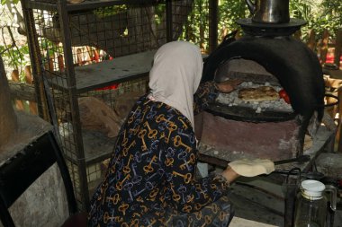 Ajloun, Ürdün. 17 Nisan 2025. Bir köy kadını Ajloun 'daki yerel bir restoranın ahşap fırınında otantik Arap ekmeği pişiriyor..