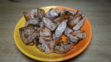 pieces of fried meat, pork in a ceramic plate on a wooden table in the kitchen