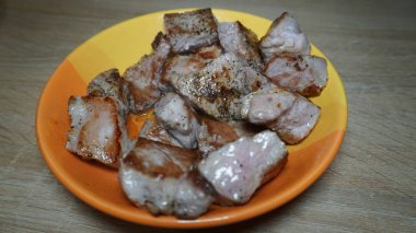 pieces of fried meat, pork in a ceramic plate on a wooden table in the kitchen