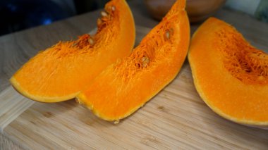 Tahta masadaki parlak turuncu balkabağı parçaları.