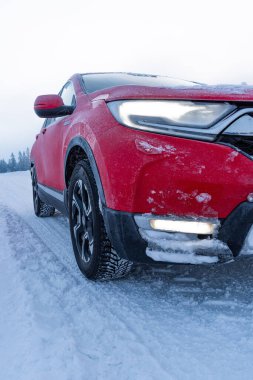 Detail on the wheel of a frozen red car.