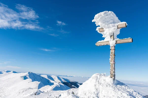 Slovak cross on the top of the Dumbier Hill in a winter landscape.