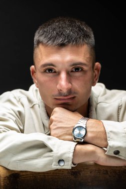Young successful stylish man. Classical portrait of a businessman dressed in a jacket with a watch on his hand.