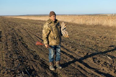 A mature hunter arranges stuffed decoy geese across the field