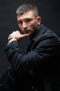 Young successful stylish man. Classical portrait of a businessman dressed in a jacket with a watch on his hand.