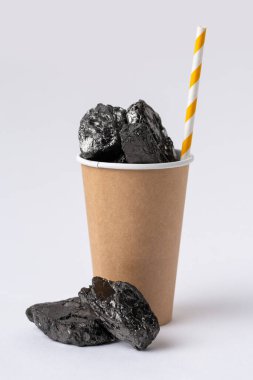 A cardboard ecological cup is filled with carbon fuel in the form of coal.