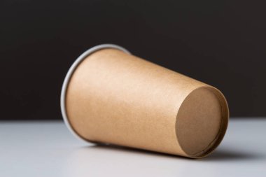 Disposable cardboard biodegradable glass on a white table, gray background.