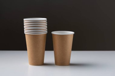 Disposable cardboard biodegradable cups on a white table, gray background.