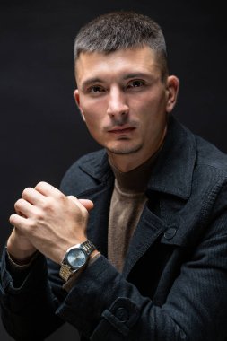 Young successful stylish man. Classical portrait of a businessman dressed in a jacket with a watch on his hand.