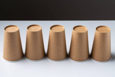 Disposable cardboard biodegradable cups on a white table, gray background.