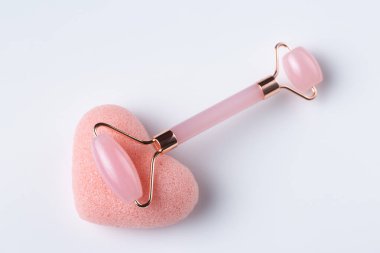 Pink Gua Sha massage tool on a white background, close-up. Rose Quartz jade roller.
