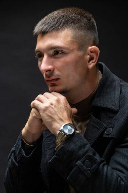 Young successful stylish man. Classical portrait of a businessman dressed in a jacket with a watch on his hand.