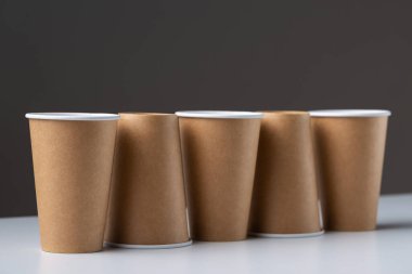 Disposable cardboard biodegradable cups on a white table, gray background.