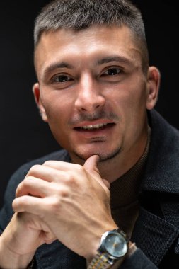 Young successful stylish man. Classical portrait of a businessman dressed in a jacket with a watch on his hand.