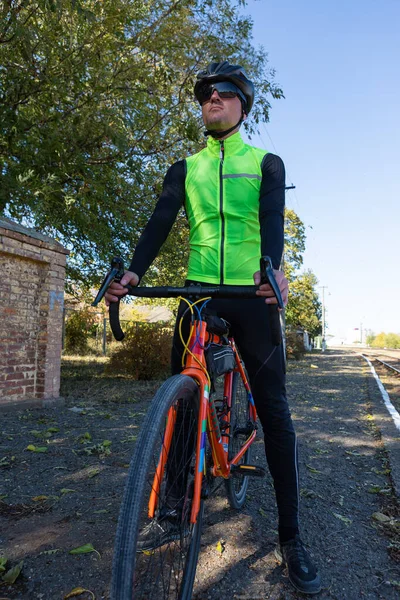 A man in clothes stands with a bicycle on an autumn sunny day. Cyclist in an urban environment.