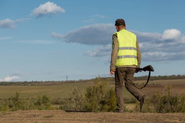 Mature man hunter with gun while walking on field.