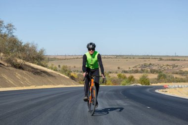 Cyclist riding bicycle on road against clear sky