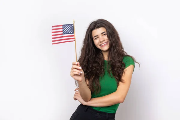 stock image A young happy girl with a smile on her face holds an American flag in her hands. Symbol of patriotism and freedom.