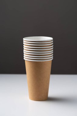 Disposable cardboard biodegradable cups on a white table, gray background.
