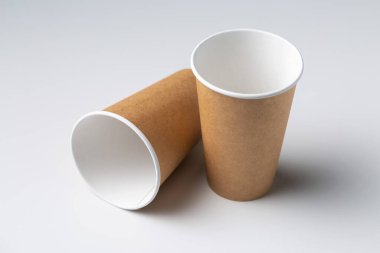 Disposable cardboard biodegradable cups on a white table, gray background.