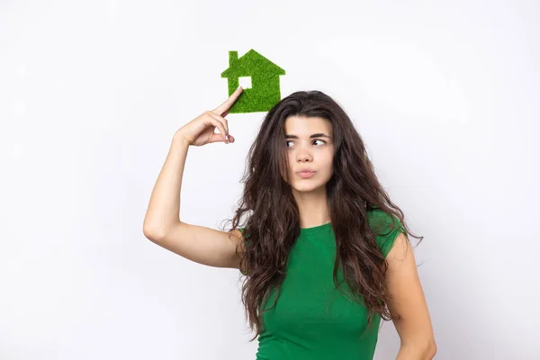 Happy house buyer. A young girl holds a model of a green house in her hands. The concept of green energy, ecology.