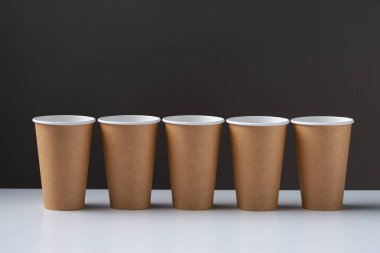 Disposable cardboard biodegradable cups on a white table, gray background.