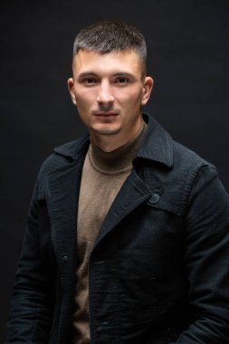 Young successful stylish man. Classical portrait of a businessman dressed in a jacket with a watch on his hand.