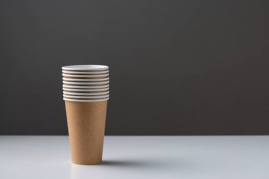 Disposable cardboard biodegradable cups on a white table, gray background.