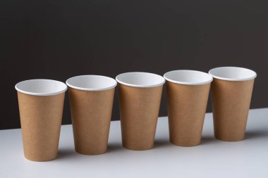 Disposable cardboard biodegradable cups on a white table, gray background.
