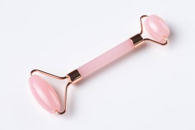 Pink Gua Sha massage tool on a white background, close-up. Rose Quartz jade roller.