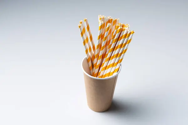 stock image Disposable cardboard biodegradable cup on a white table with a straw.