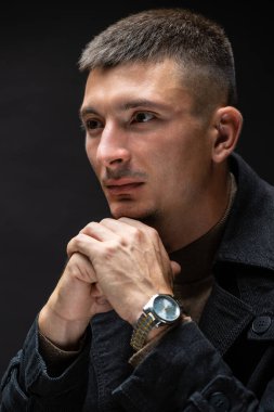 Young successful stylish man. Classical portrait of a businessman dressed in a jacket with a watch on his hand.