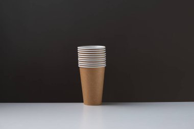 Disposable cardboard biodegradable cups on a white table, gray background.