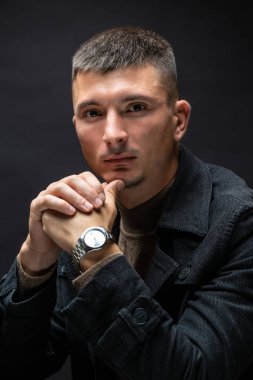 Young successful stylish man. Classical portrait of a businessman dressed in a jacket with a watch on his hand.