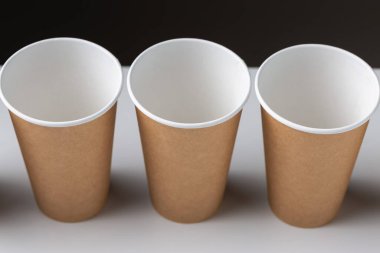 Disposable cardboard biodegradable cups on a white table, gray background.