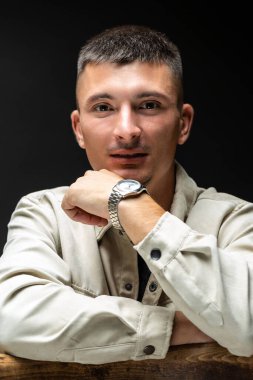 Young successful stylish man. Classical portrait of a businessman dressed in a jacket with a watch on his hand.