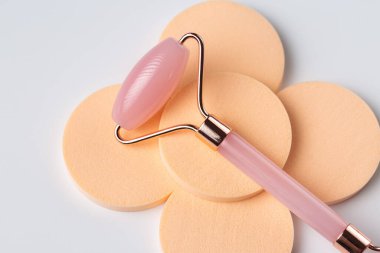 Pink Gua Sha massage tool on a white background, close-up. Rose Quartz jade roller.