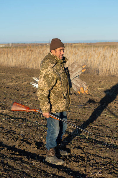 Взрослый охотник устраивает чучело приманки гусей через поле