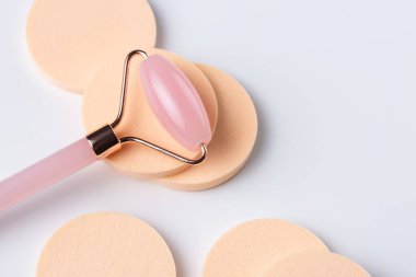 Pink Gua Sha massage tool on a white background, close-up. Rose Quartz jade roller.