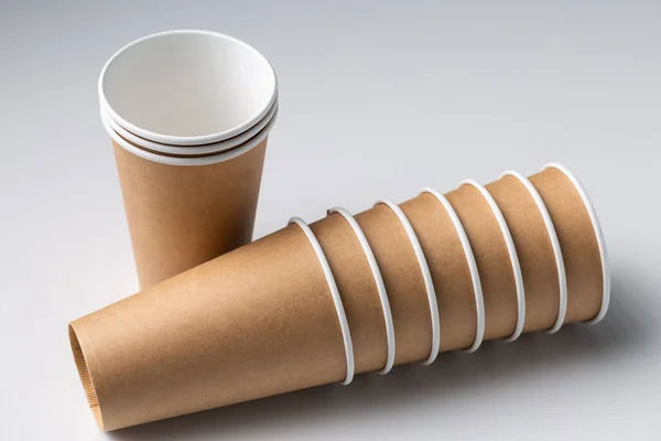 Disposable cardboard biodegradable cups on a white table, gray background.