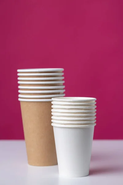 stock image Disposable cardboard biodegradable glass on a white table, red background.